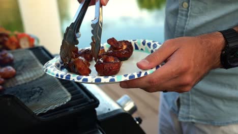 Manos-Plateando-Champiñones-Asados-Desde-La-Parrilla-Del-Patio-Trasero-Con-Canal-De-Agua-En-El-Fondo