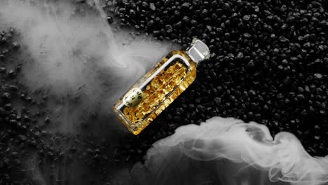 Waves-of-white-smoke-run-across-bottle-of-24k-Gold-on-black-stone-background