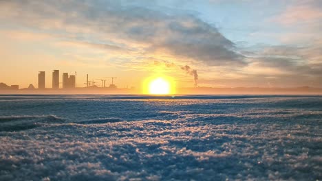 Mar-Congelado-Al-Atardecer-Con-Fondo-Del-Horizonte-De-La-Ciudad,-Impresionante-Paisaje-Invernal