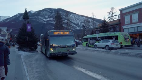 Autobuses-Eléctricos-En-Servicio-En-La-Calle-Llegando-A-La-Estación-De-Autobuses-Por-La-Noche-En-El-Centro-De-Banff,-Alberta,-Canadá