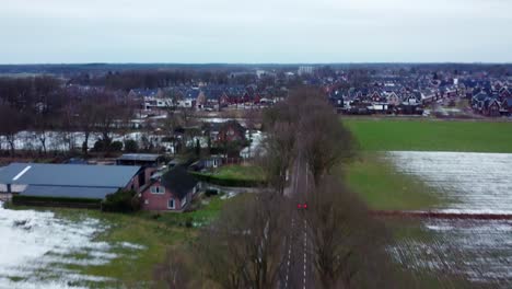 Aerial-view-above-car-driving-on-road-through-farm-fields-in-Bergeijk,-Netherlands