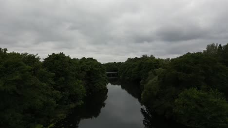 Drohnenaufnahme-Des-Flusses-Gudenå,-Fliegt-über-Und-Entlang-Des-Flusses-Auf-Dem-Weg-Zu-Einer-Kleinen-Brücke,-Die-Drohne-Fliegt-Weiter-über-Die-Brücke-Und-Zeigt-Schließlich-Eine-Wunderschöne-Landschaft