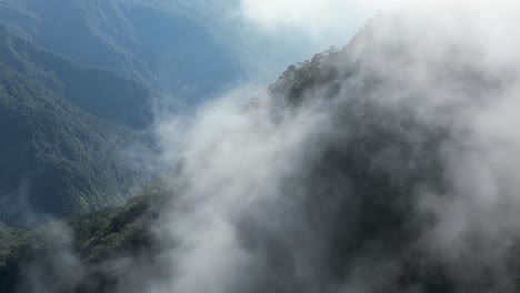 Vuelo-Aéreo-Natural-A-Través-De-Nubes-Retroiluminadas-En-Una-Empinada-Montaña-Selvática