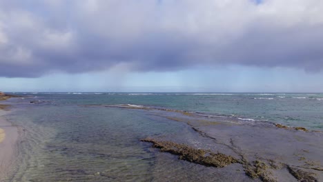 Una-Plataforma-De-Nubes-Se-Cierne-Sobre-Las-Pozas-De-Marea-Y-Las-Olas-Del-Océano-Pacífico-Mientras-Las-Olas-Ruedan-Suavemente-Hacia-La-Costa-Rocosa-Cerca-De-Diamond-Head-Oahu-Hawaii