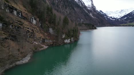 Klöntalersee-Switzerland-Glarus-smooth-aerial-of-lake-where-it-meets-mountain-edge