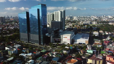 Drone-flying-around-the-Ayala-Malls-Circuit,-sunny-evening-in-Makati,-Philippines