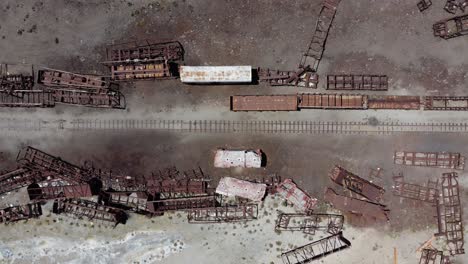 Aerial-looks-directly-down-onto-old-railroad-train-graveyard,-Bolivia