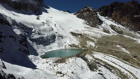 Mountain-alpine-aerial-descends-to-lagoon-on-slope-in-Bolivian-Andes