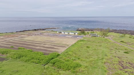 Drone-view-offering-a-wide-global-perspective-of-the-salt-pans,-salt-barn,-and-surroundings-at-Pointe-au-Sel-in-Saint-Leu,-Reunion-Island,-with-an-orbit-left-movement