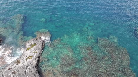 Drone-view,-low-altitude-rotational-movement-above-the-blue-waters-and-rocks-of-Pointe-au-Sel-in-Saint-Leu,-Reunion-Island