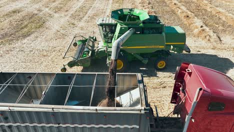 John-Deere-Mähdrescher-Entlädt-Einen-Trichter-Mit-Raps-In-Einen-Sattelschlepper