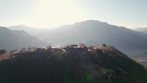Mountain-Range-Sunrise-sun-Shines-Above-Takeda-Castle-Ruins-Japanese-Landscape-in-Hyogo-Asago,-Aerial-Drone-Shot