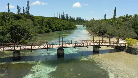 A-wooden-footbridge-over-a-shallow-water-channel-between-the-Isle-of-Pines-and-Kotomo-Island-New-Caledonia-aerial