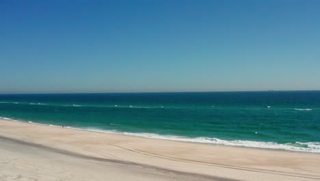 Drone-shot-captures-the-serene-beauty-of-Southhampton-Beach-in-the-Hamptons,-overlooking-the-vast-sea-and-ocean,-offering-a-breathtaking-view-from-New-York