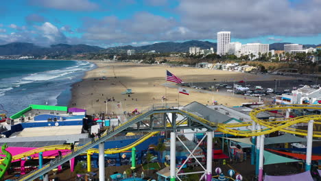 Aerial-view-over-the-California-state-and-US-flag-on-top-of-the-Santa-Monica-pier-in-sunny-LA
