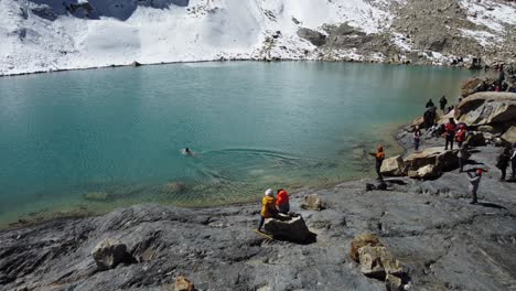 Female-tourist-dives,-swims-in-snowy-emerald-lagoon-in-Bolivian-Andes