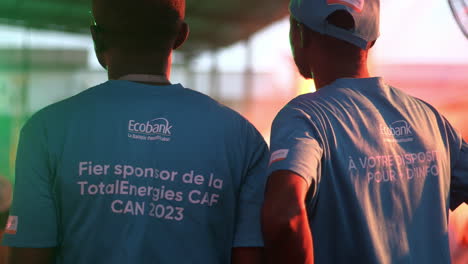 Hombres-Con-Camisetas-De-Ecobank-En-Una-Zona-De-Fans-Durante-El-Partido-De-Costa-De-Marfil,-Copa-Africana-De-Naciones-2023,-Abidjan