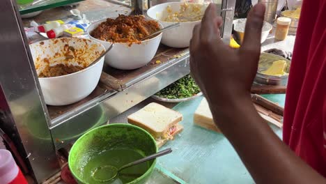 Closeup-shot-of-Indian-styled-sandwiches-getting-sliced-into-halves-at-a-roadside-stall-in-Kolkata,-India