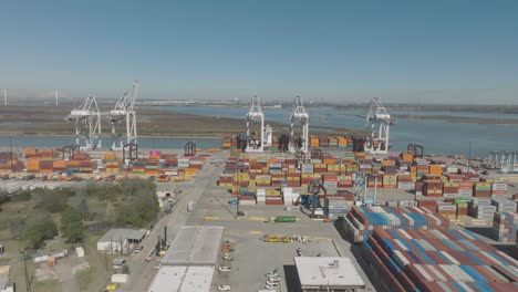 An-aerial-establishing-shot-captures-trucks,-forklifts,-and-cranes-loading-ships-and-moving-cargo-at-the-Port-of-Houston's-Barbours-Cut-Container-Terminal-in-Houston,-Texas