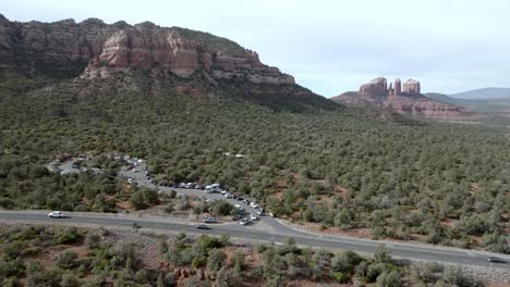 Red-rock-mountains-and-buttes-in-Sedona,-Arizona-with-cars-driving-on-the-road-with-drone-video-wide-shot-stable