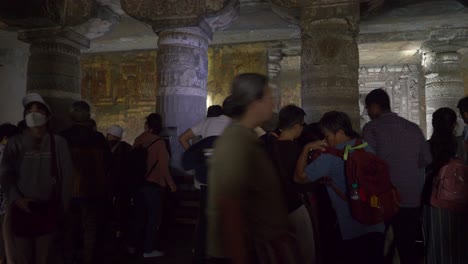 Japanese-tourists-watching-rock-carvings-and-painted-mural-artwork-at-the-wall-of-medieval-era-Ajanta-caves