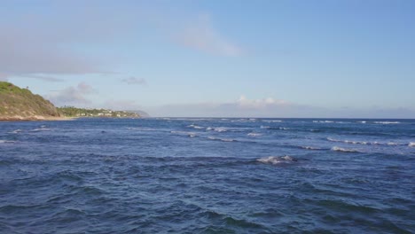 Drohnenaufnahmen-über-Den-Weißen,-Blauen-Wellen-Des-Pazifiks-An-Einem-Sonnigen-Tag-Auf-Oahu,-Hawaii,-Mit-Blauem-Himmel-Und-Der-Küste-Der-Hawaiianischen-Insel-Auf-Der-Linken-Seite