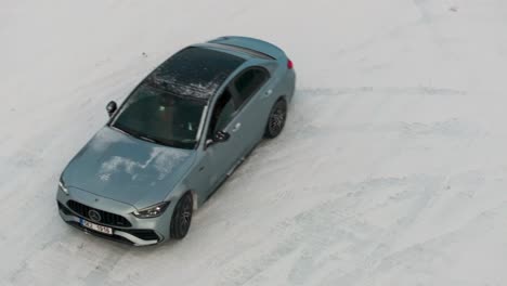 Aerial-view-of-car-slide-sideways-on-snowy-slippery-road,-drift-event