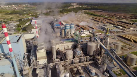 Toma-Aérea-En-órbita-De-Una-Gran-Planta-Industrial-En-Un-Día-Soleado:-Sale-Mucho-Humo-De-Las-Chimeneas