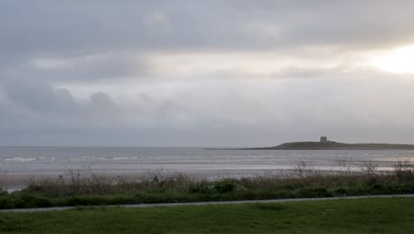 Zeitraffer-Mit-Blick-Auf-Den-Strand-Von-Skerries-Mit-Dem-Martello-Tower-Auf-Shenick-Island-In-Der-Ferne,-Während-Graue-Regenwolken-Vorbeiziehen,-Irland