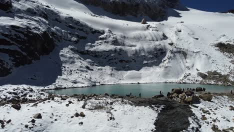 Open-water-lagoon-on-snowy-alpine-mountain-slope,-Laguna-Charquini-BOL