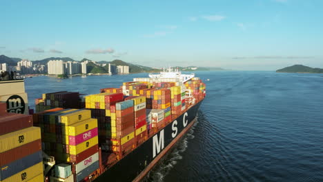 Un-Primer-Plano-Hacia-Atrás-Con-Un-Dron-De-Un-Gran-Buque-Portacontenedores-MSC-Saliendo-De-Hong-Kong