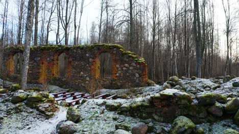 Abandoned-church-boulder-wall-remains-with-new-seats-in-bare-tree-forest
