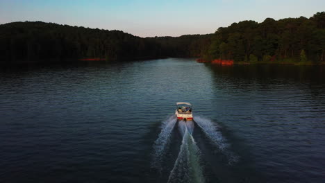 Forwards-tracking-of-small-motor-boat-driving-on-lake-surface-at-sunset