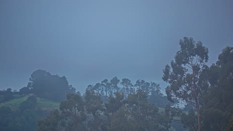 Timelapse-shot-of-fog-passing-over-highlands-covered-green-vegetation-along-rural-countryside-during-morning-time