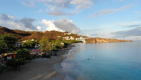 Houses-on-a-tropical-sandy-beach,-aerial-establishing-shot