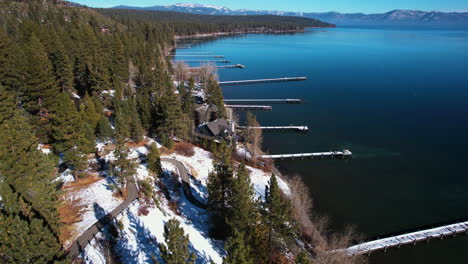 Vista-Aérea-De-Los-Muelles-De-Madera-Del-Lago-Tahoe-En-El-Soleado-Día-De-Invierno,-Aguas-Tranquilas-Y-Bosque-De-Pinos