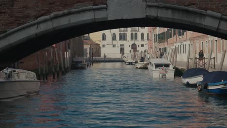 Blick-Auf-Den-Venezianischen-Kanal-Unter-Einer-Bogenbrücke,-Ruhiges-Wasser