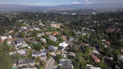 Encino-hills,-California-with-suburban-homes-and-lush-greenery,-mountain-backdrop,-aerial-view