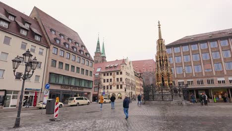 Turistas-Que-Visitan-La-Hermosa-Fuente-En-El-Mercado-Central-De-Nuremberg,-Alemania,-Después-De-Una-Ligera-Nevada