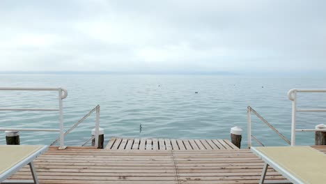 El-Disparo-Desde-El-Muelle-De-Madera-Del-Solarium-Retro-Revela-El-Ambiente-Tranquilo-Y-Azul-Del-Lago-De-Garda