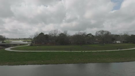 An-aerial-following-shot-shows-a-male-cyclist-riding-through-Exploration-Green-on-a-dark-cloudy-day-in-Clear-Lake,-Houston,-Texas