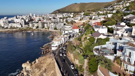 Cape-Town,-South-Africa,-aerial-drone-over-a-busy-coastal-road-with-downtown-in-the-background