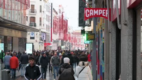 On-a-bustling-commercial-street,-shoppers-enter-the-Camper-store,-a-Spanish-multinational-specializing-in-manufacturing-and-retailing-footwear,-located-in-Madrid,-Spain