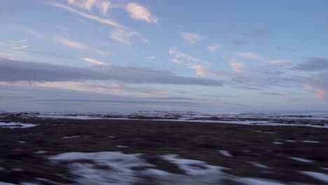 Evening-view-from-a-moving-car,-Iceland's-rugged-terrain-under-a-serene-sky,-point-of-view-shot