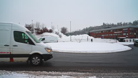 Mehrere-Verschiedene-Autos-Fahren-An-Einem-Bewölkten-Wintertag-Um-Einen-Schneebedeckten-Kreisverkehr