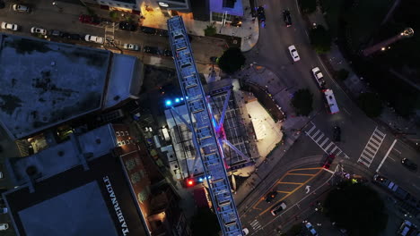 Top-down-rotating-shot-of-Ferris-Wheel-and-surrounding-buildings-in-urban-borough-at-dusk