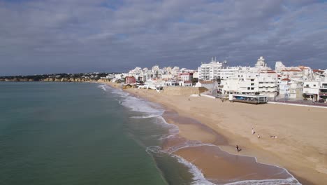 Tranquil-beach-at-holiday-resort-and-city-Armacao-de-Pera-in-Portugal,-aerial