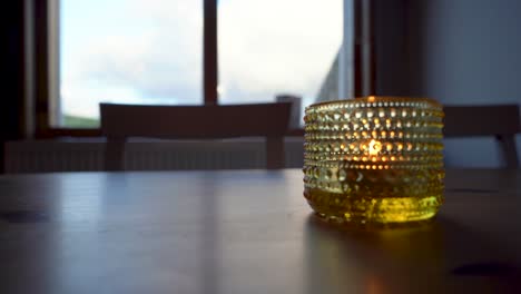 Goldener-Kerzenhalter-Auf-Dem-Tisch-Mit-Weichem-Fokus,-Warme-Innenstimmung,-Dämmerungslicht-Aus-Dem-Fenster