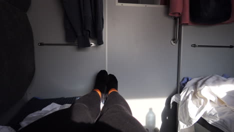 Laying-down-in-a-train-coupe-on-Ukrainian-Railways-Ukrzaliznycia-East-Europe,-sleeper-train-with-two-beds-and-sheets,-traveling-in-comfort-to-Kyiv-Ukraine,-sleeping-on-a-long-train-ride,-4K-tilting-up