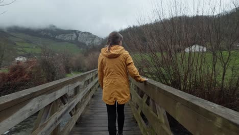 A-young-lady-looks-at-the-river-below-while-walking-across-a-timber-bridge